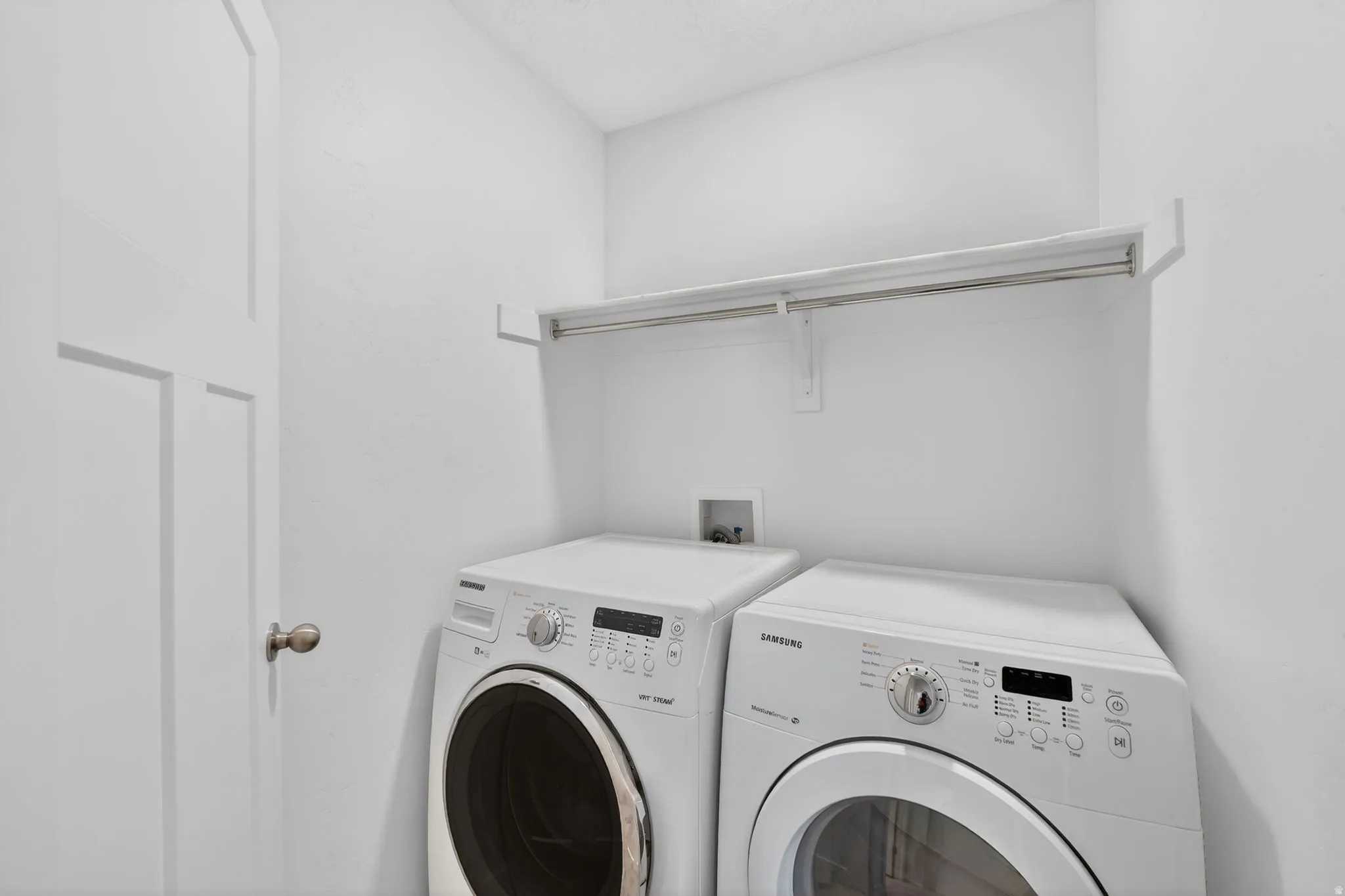 Dedicated laundry space featuring a white panel door, overhead shelving, and a hanging rod