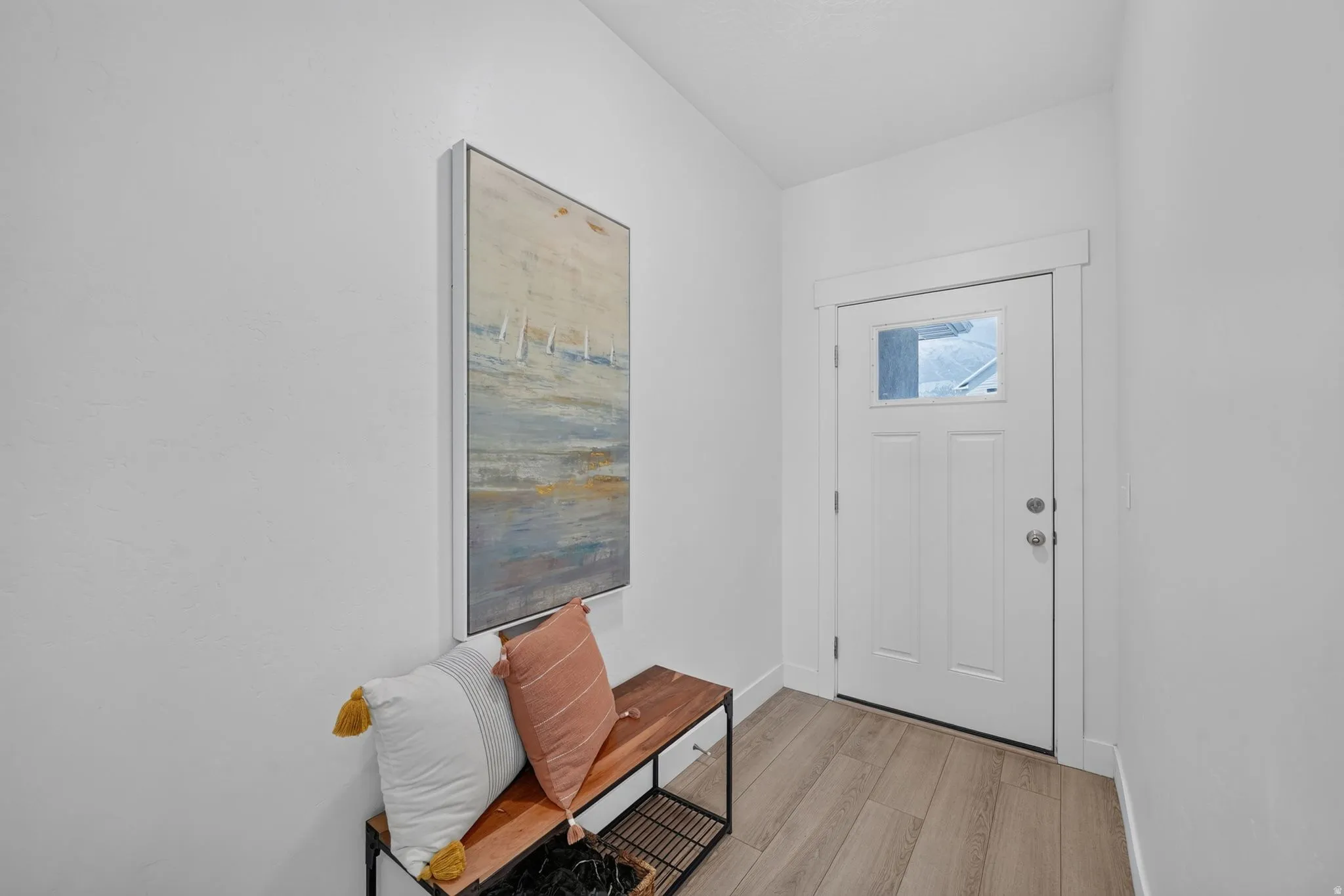 Entryway featuring wood-finish flooring, a white paneled door with a clear glass insert, and crisp white walls
