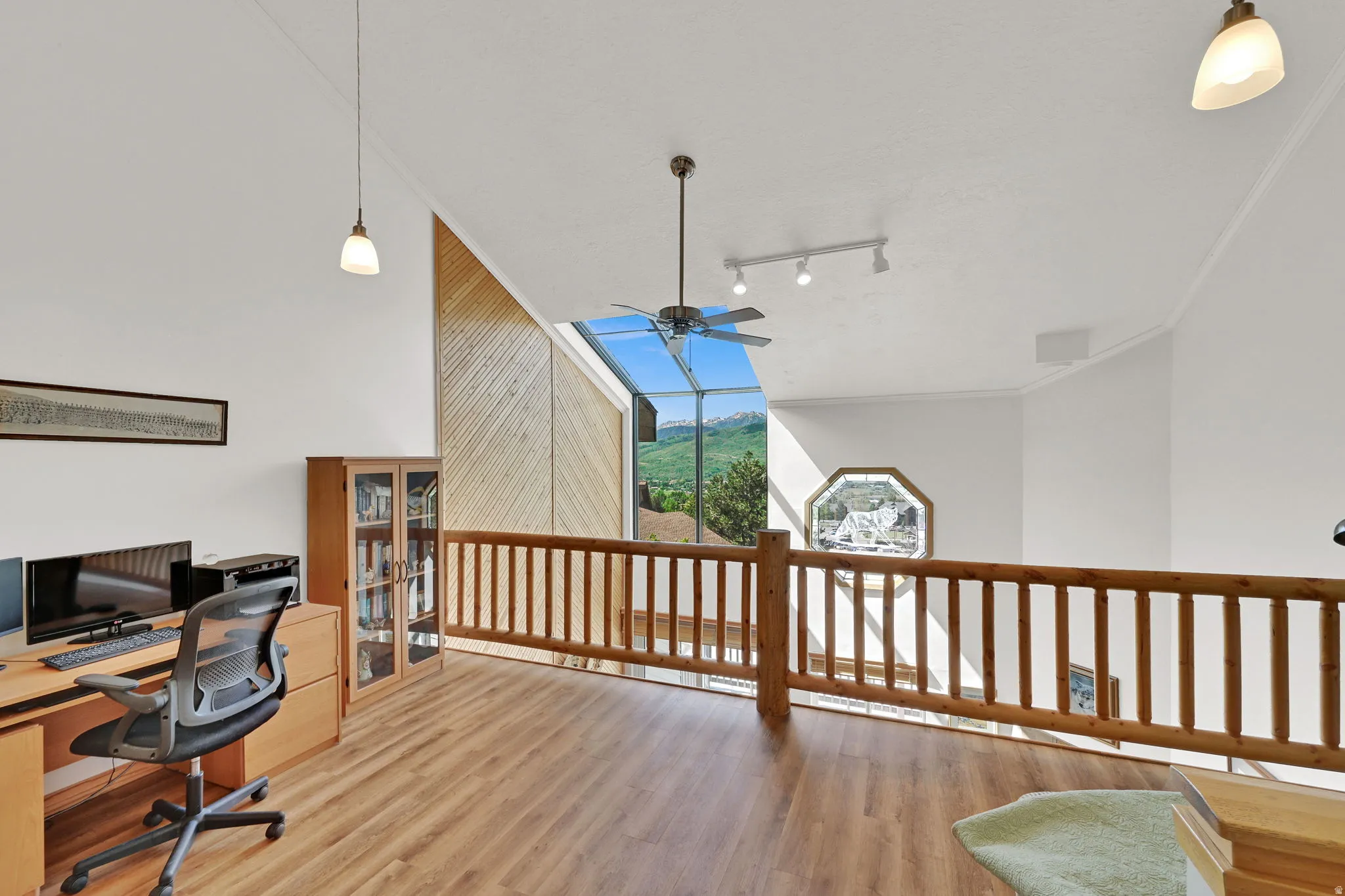 Loft area featuring wood-finish flooring, a wood baluster railing, sloped ceilings, and clerestory windows