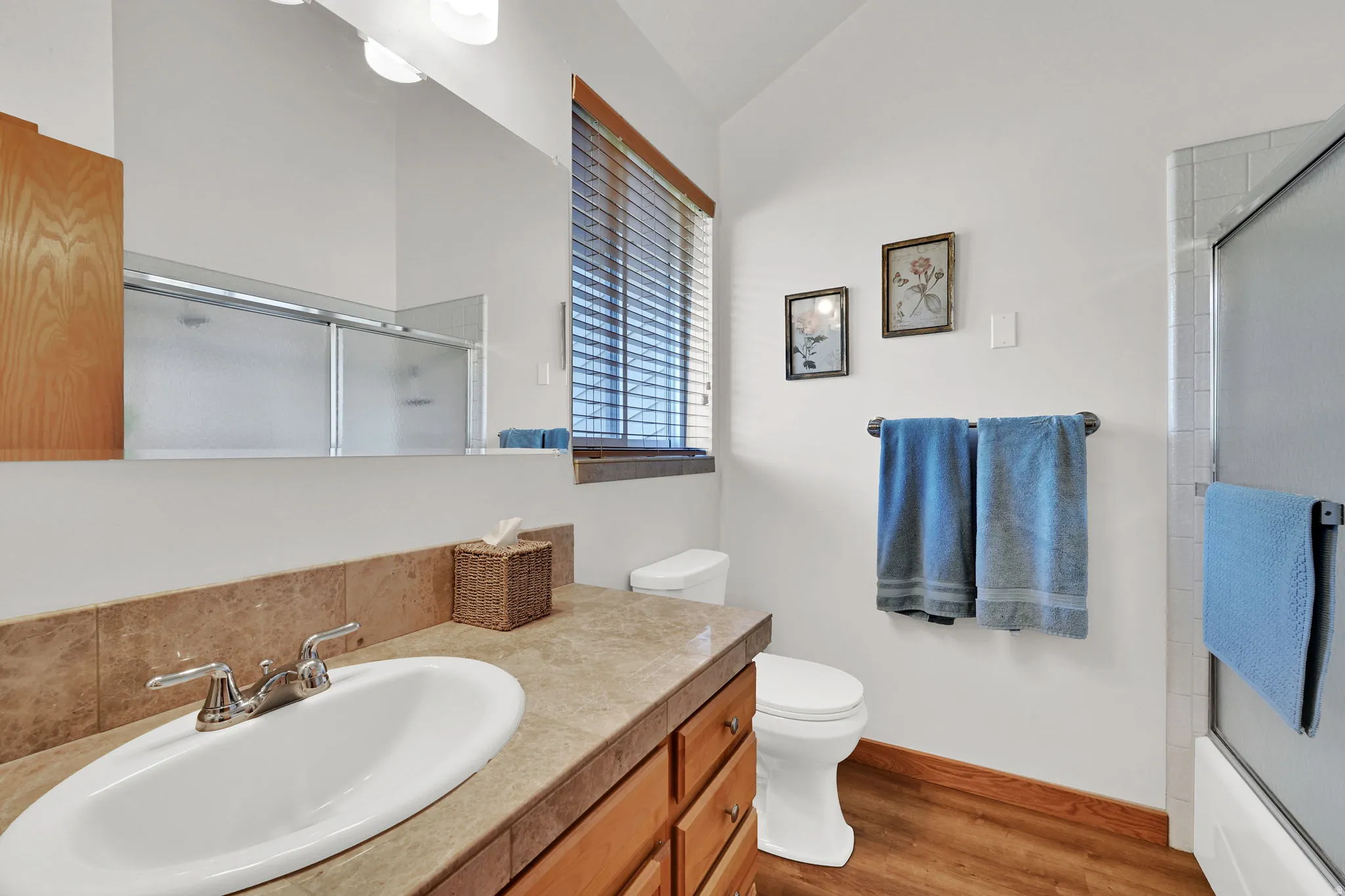 Primary Bathroom featuring a warm wood-finish vanity with a tile countertop, an undermount sink, and a chrome faucet