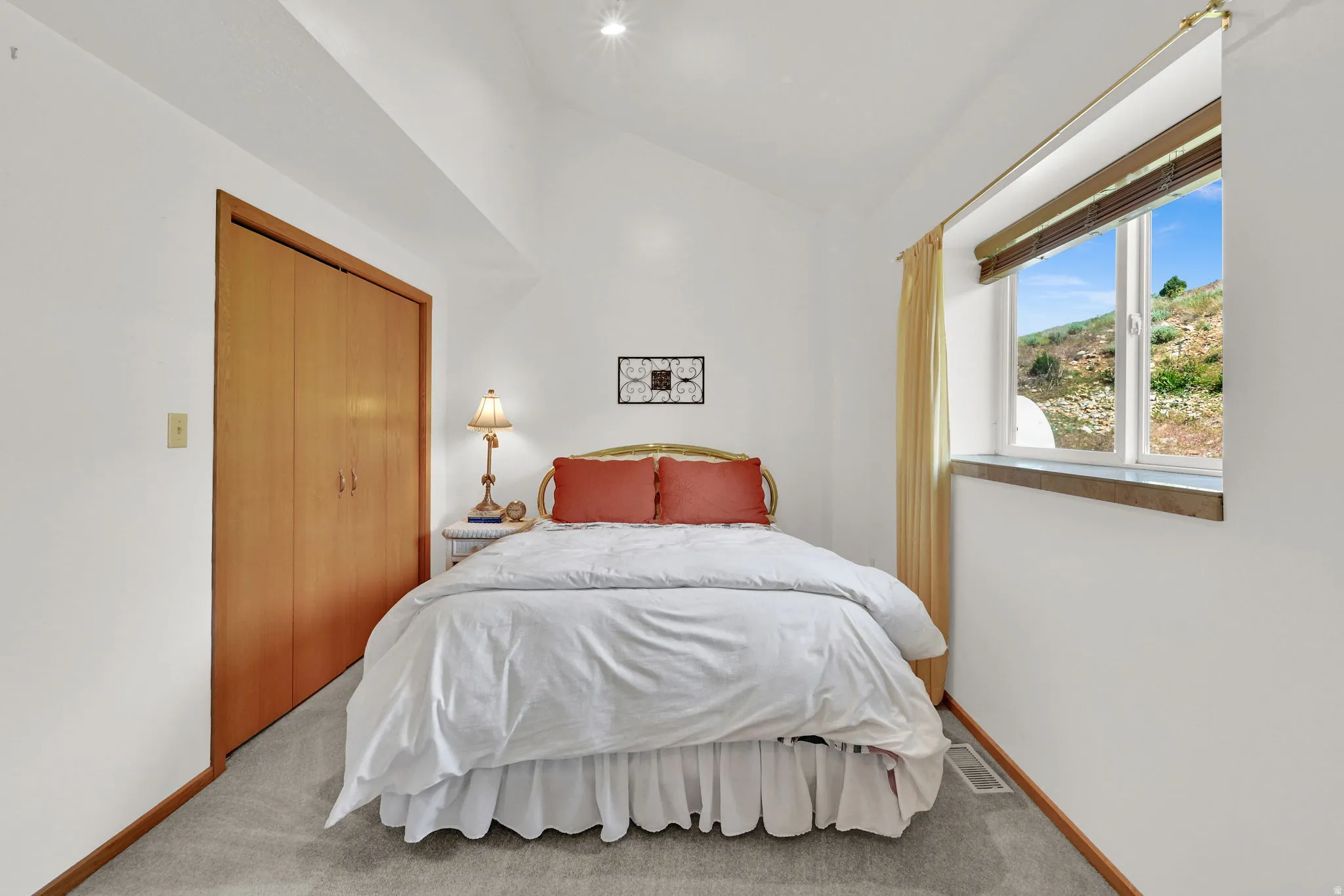 Vaulted ceiling room featuring a large window with exterior scenery, light-toned wood-finish bi-fold closet doors, recessed lighting, and grey carpet