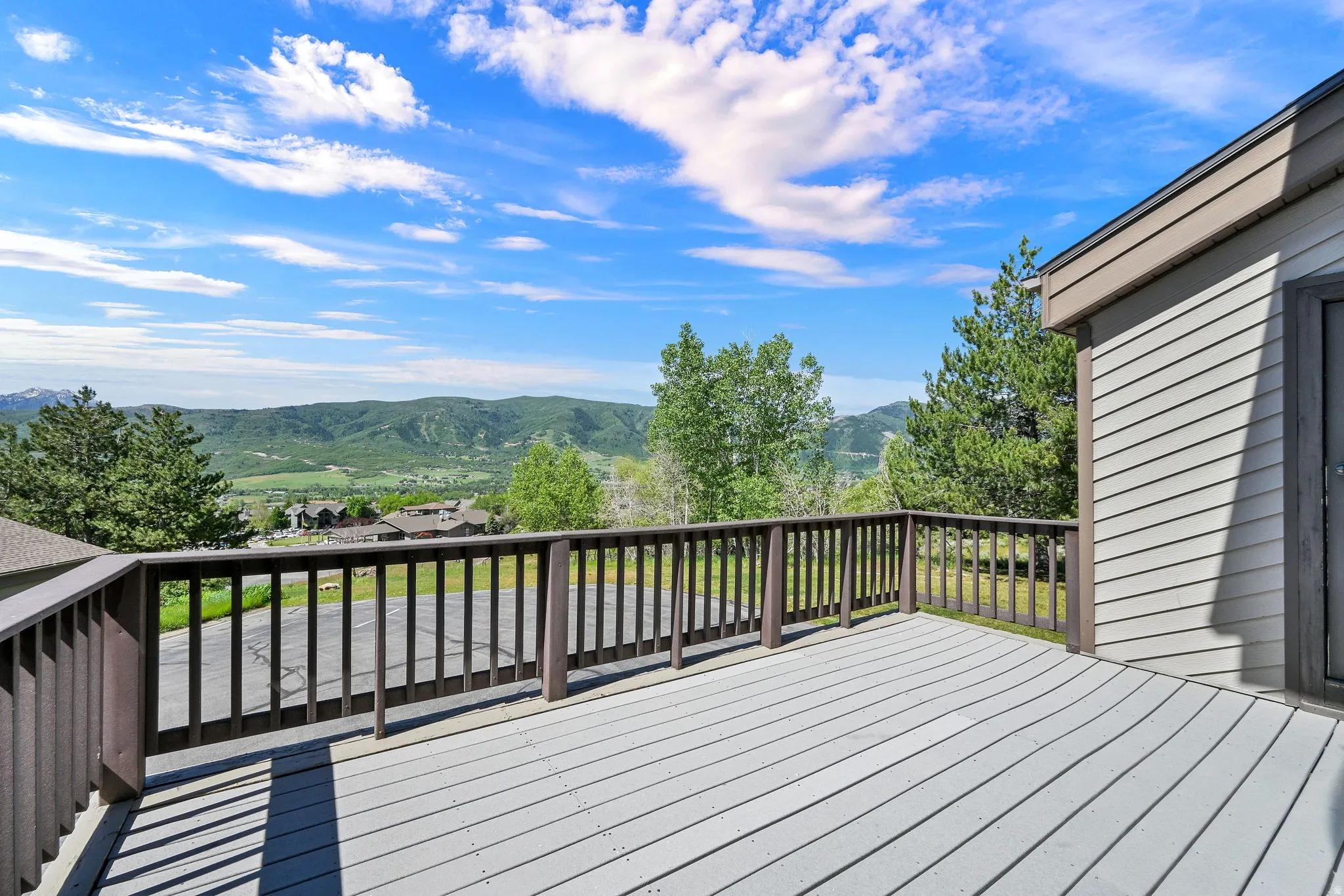 Deck View looking west at Nordic Valley Ski Resort.  Spacious outdoor deck featuring gray composite decking, a dark wood railing, and a siding exterior