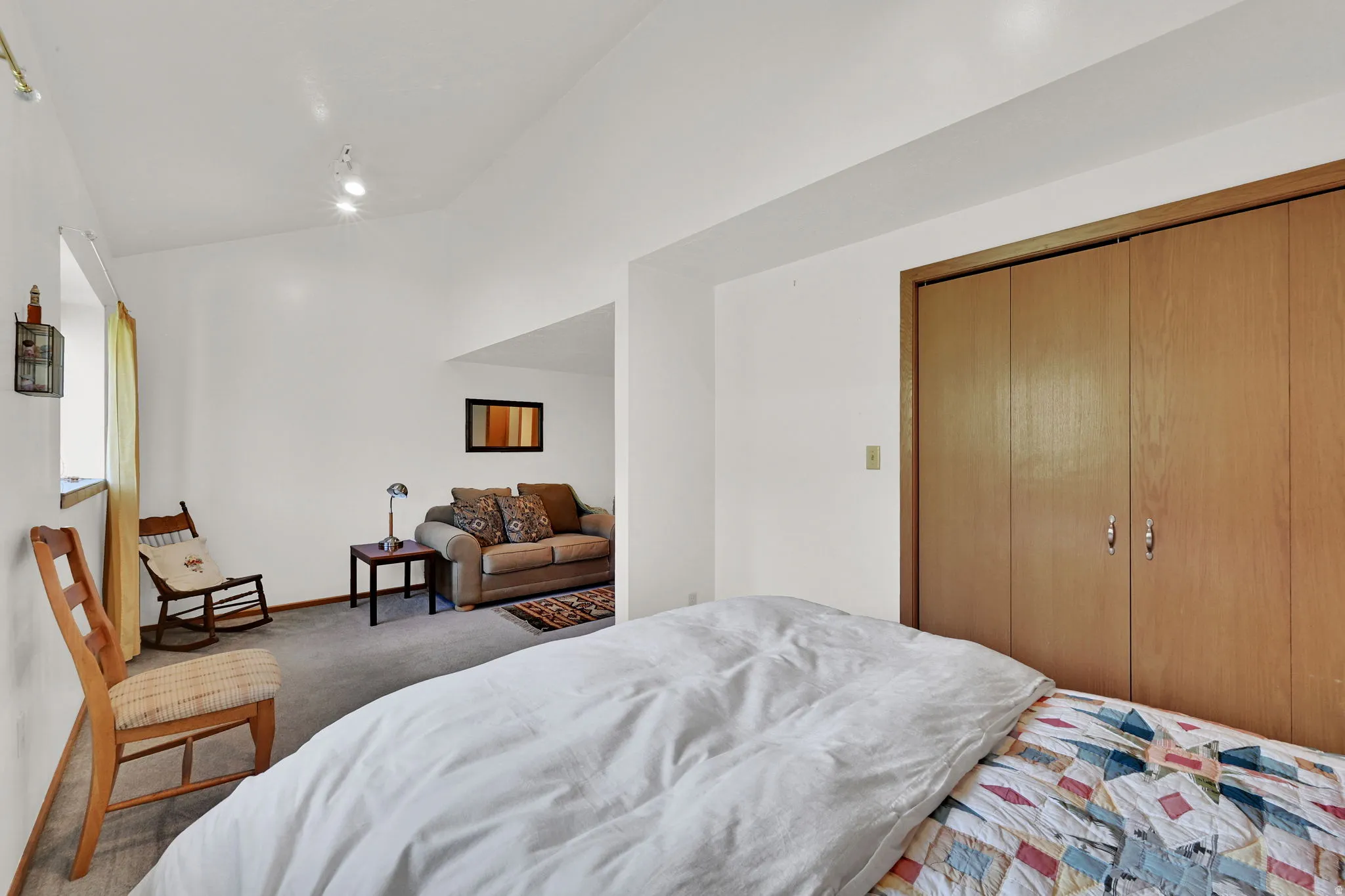 Spacious room with white walls, track lighting, and wood-finish bi-fold closet doors