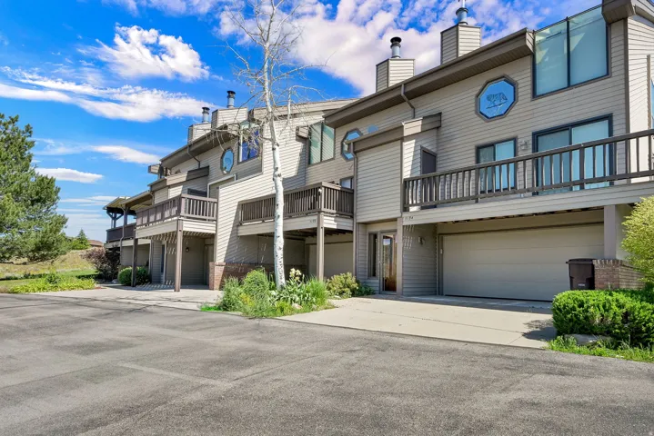 Multi-level exterior featuring horizontal siding, integrated garages, private balconies with wood railings, and a prominent round window