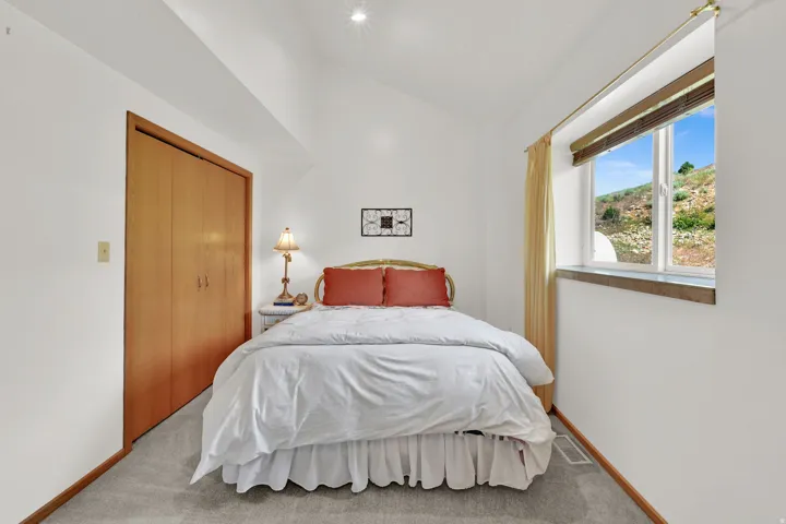 Vaulted ceiling room featuring a large window with exterior scenery, light-toned wood-finish bi-fold closet doors, recessed lighting, and grey carpet