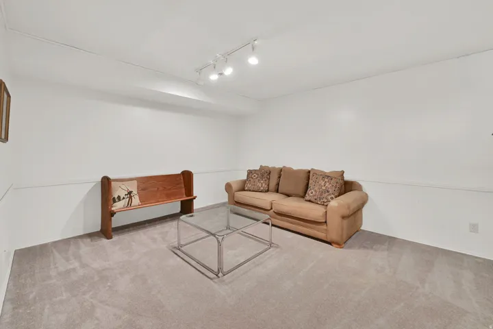 Carpeted room with white walls and track lighting
