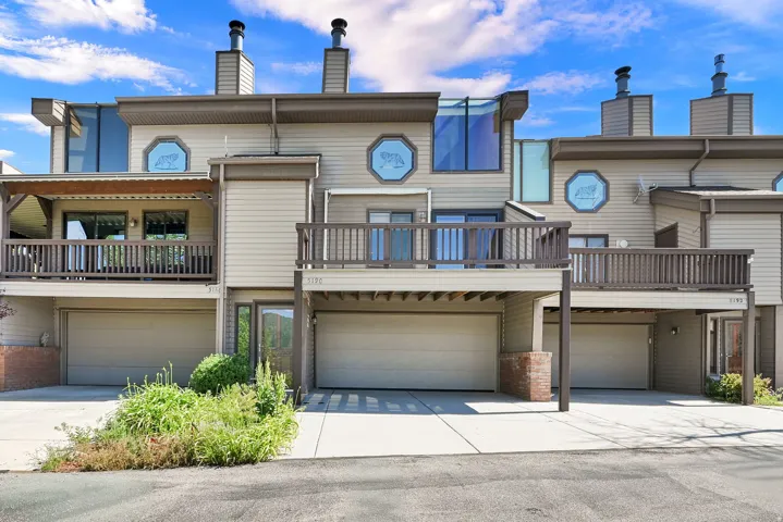 Multi-level exterior featuring tan siding, brown trim, and multiple balconies with dark wood railings