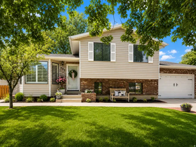 Split-level residence featuring a brick and siding exterior, an attached two-car garage with decorative hardware, and a concrete driveway