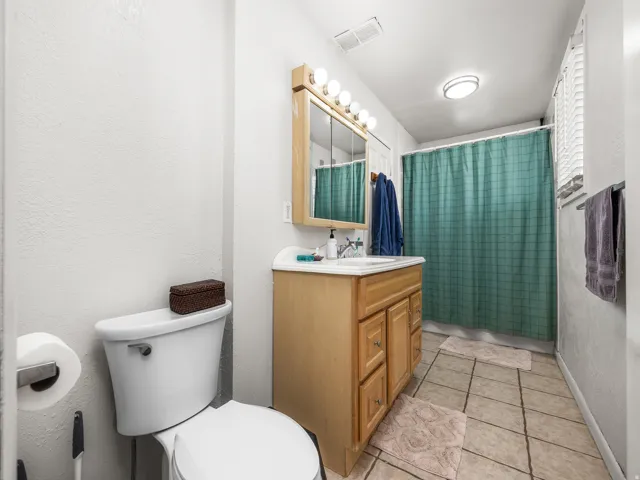 Bathroom featuring a single vanity with wood-finish cabinetry, a white integrated sink, and an overhead light fixture with five bulbs