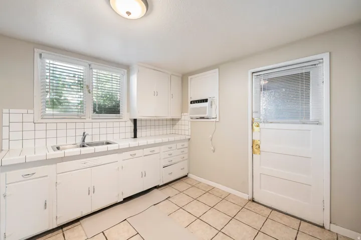 Kitchen with white cabinetry, tile countertops, and a dual basin sink
