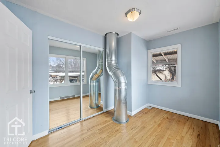 Room featuring wood-finish flooring, light blue walls, and a white six-panel door