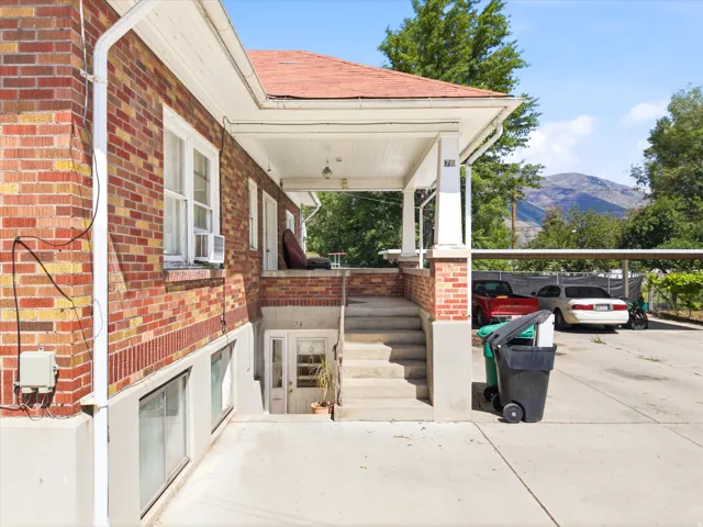 Brick exterior with a covered porch, concrete steps, and a separate basement entrance