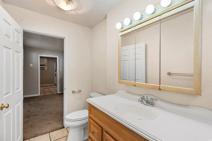 Bathroom featuring a single vanity with wood-finish cabinetry, a white countertop with an integrated sink, and a mirrored medicine cabinet