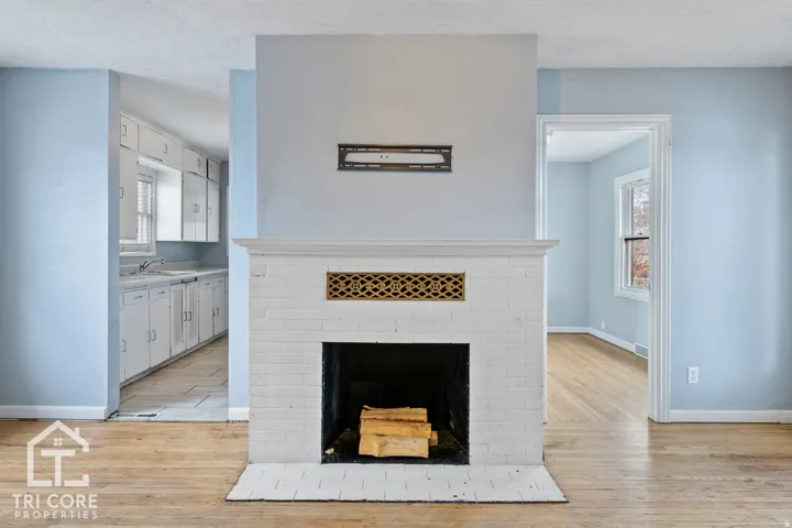 White brick fireplace with an ornate gold-tone vent and classic mantel