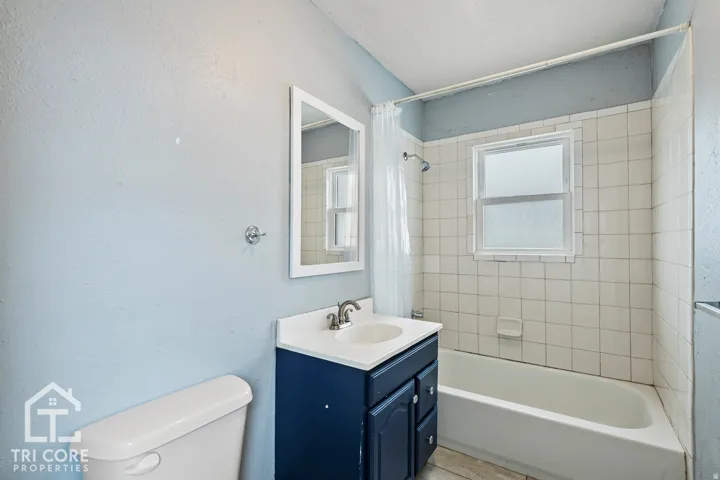 Bathroom featuring a white bathtub, ceramic tile surround, and a window with frosted glass