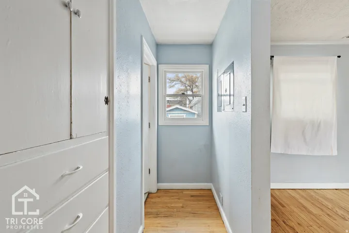 Hallway featuring built-in cabinetry, wood-finish flooring, and a white framed window