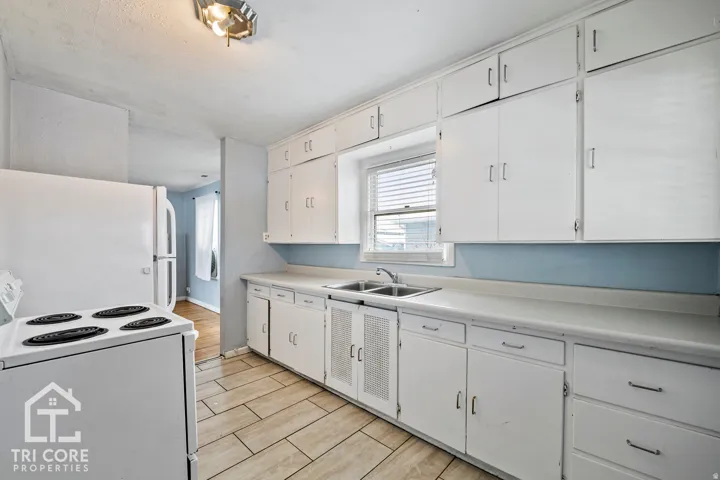 Galley kitchen featuring white cabinetry, light countertops, and tile flooring