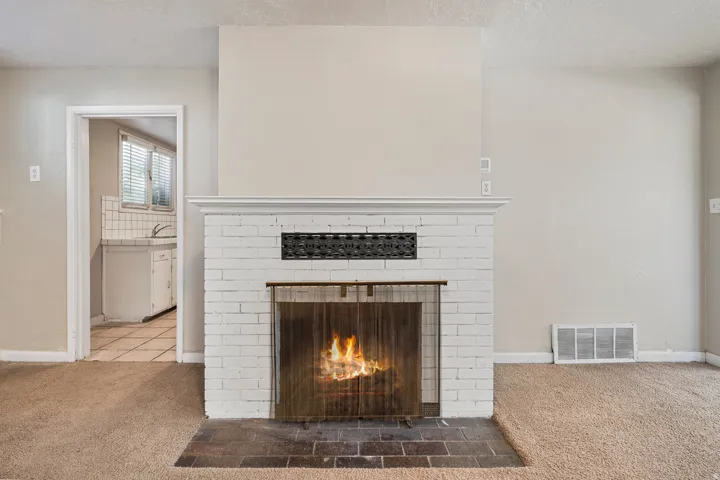 Painted brick fireplace with a decorative metal screen, complemented by a hearth of dark-toned tile