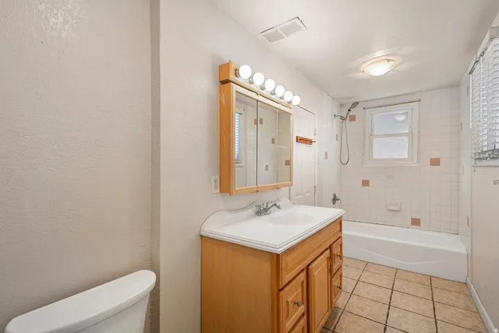 Bathroom featuring a wood-finish vanity with an integrated sink and countertop, a medicine cabinet with mirrored doors, and a five-bulb vanity light fixture