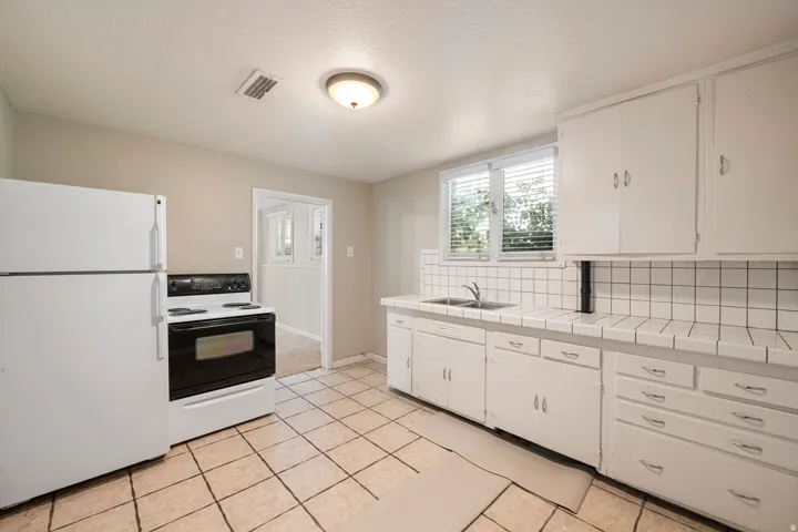 Kitchen featuring white cabinetry, tile countertops, and a white appliance package
