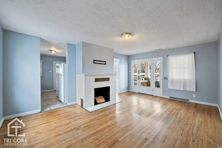 Living area featuring wood-finish flooring, a white brick fireplace with a decorative mantel, and light blue wall tones