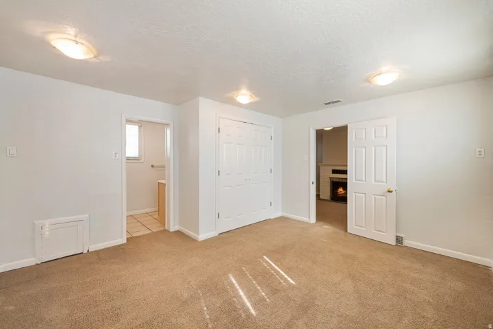 Carpeted room featuring white walls, a bi-fold closet, and overhead flush-mount lighting