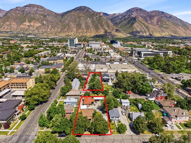 Aerial perspective of a neighborhood featuring residential structures and surrounding infrastructure, with prominent mountains in the background