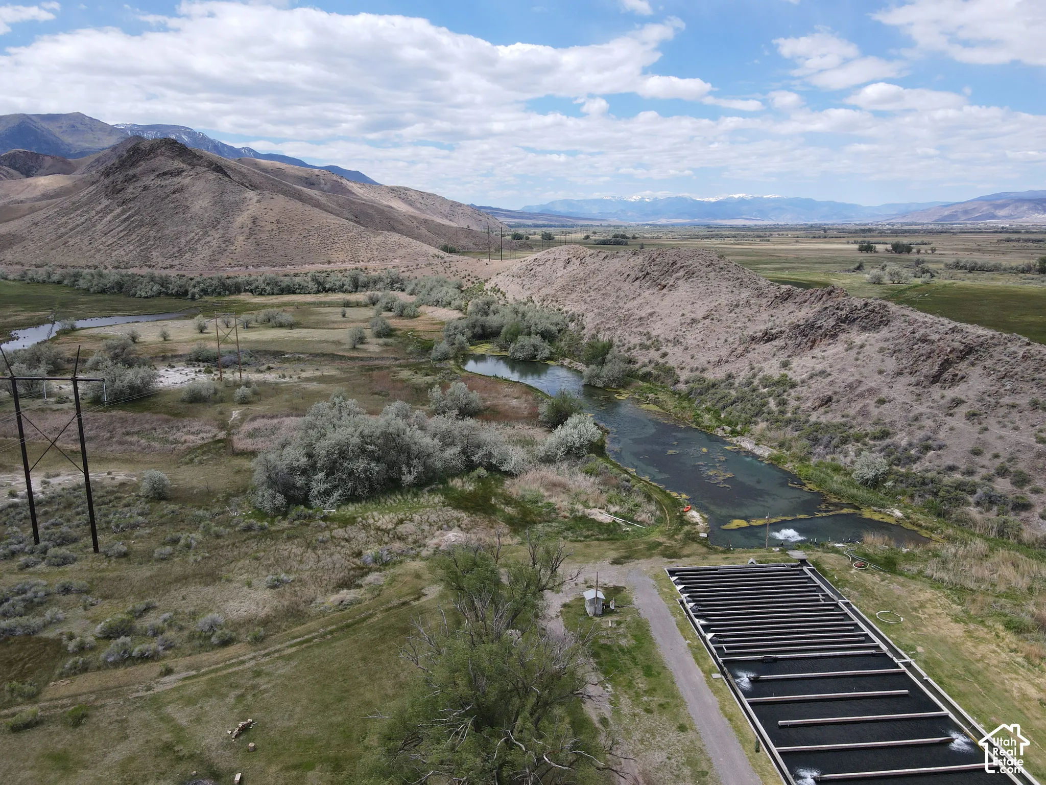 Expansive rural landscape featuring a river, mountainous terrain, and a large aquaculture facility