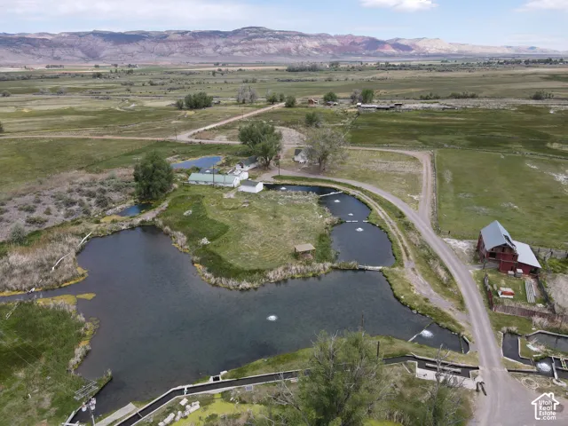 Expansive property featuring multiple ponds with water aeration, a red barn with a metal roof, a white outbuilding, and a gravel road network