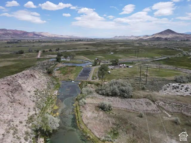 Expansive open terrain featuring a natural waterway, a small agricultural development, and distant mountains