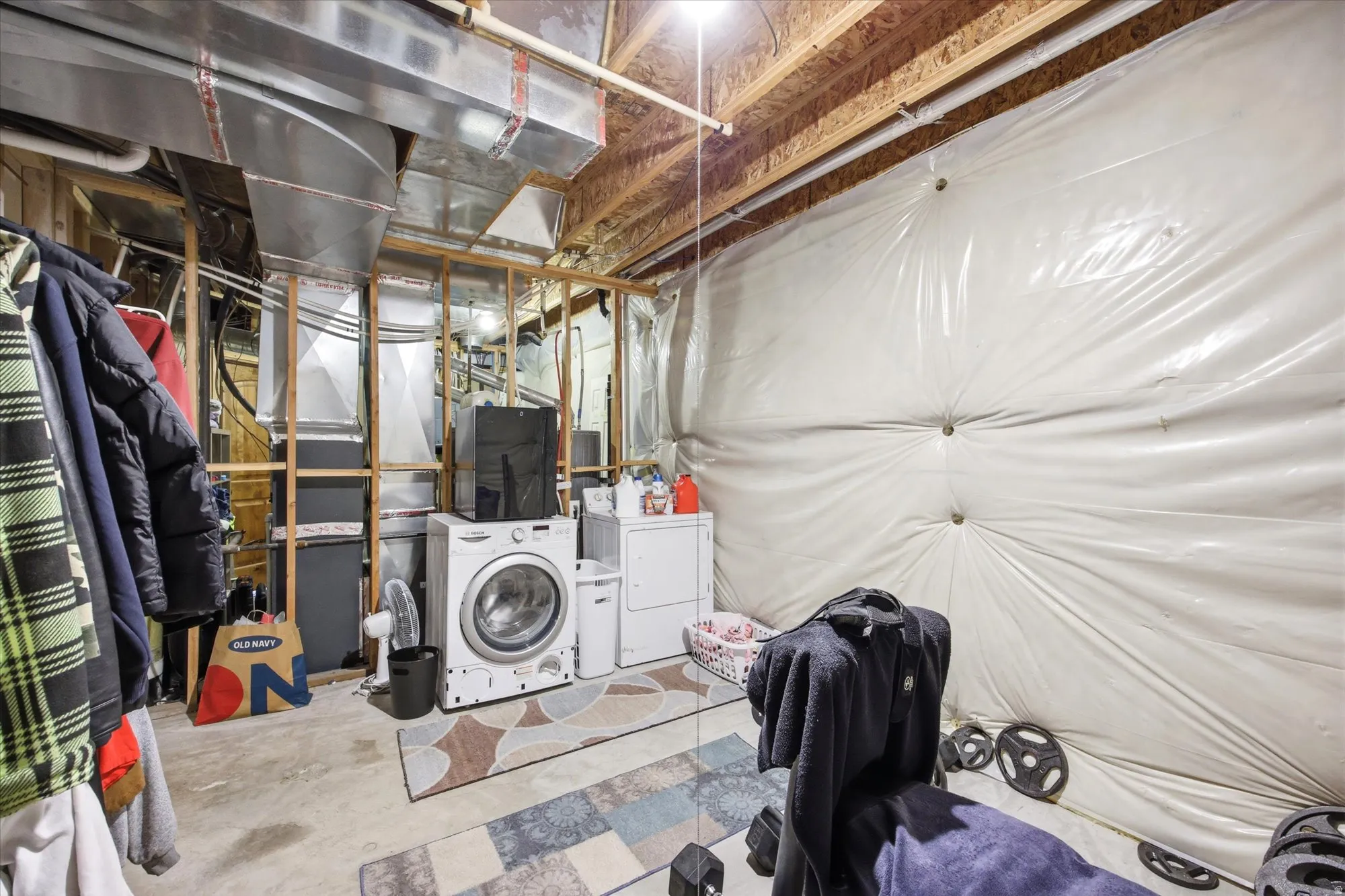 Unfinished basement space with exposed wooden joists and framing, showcasing a visible ductwork system