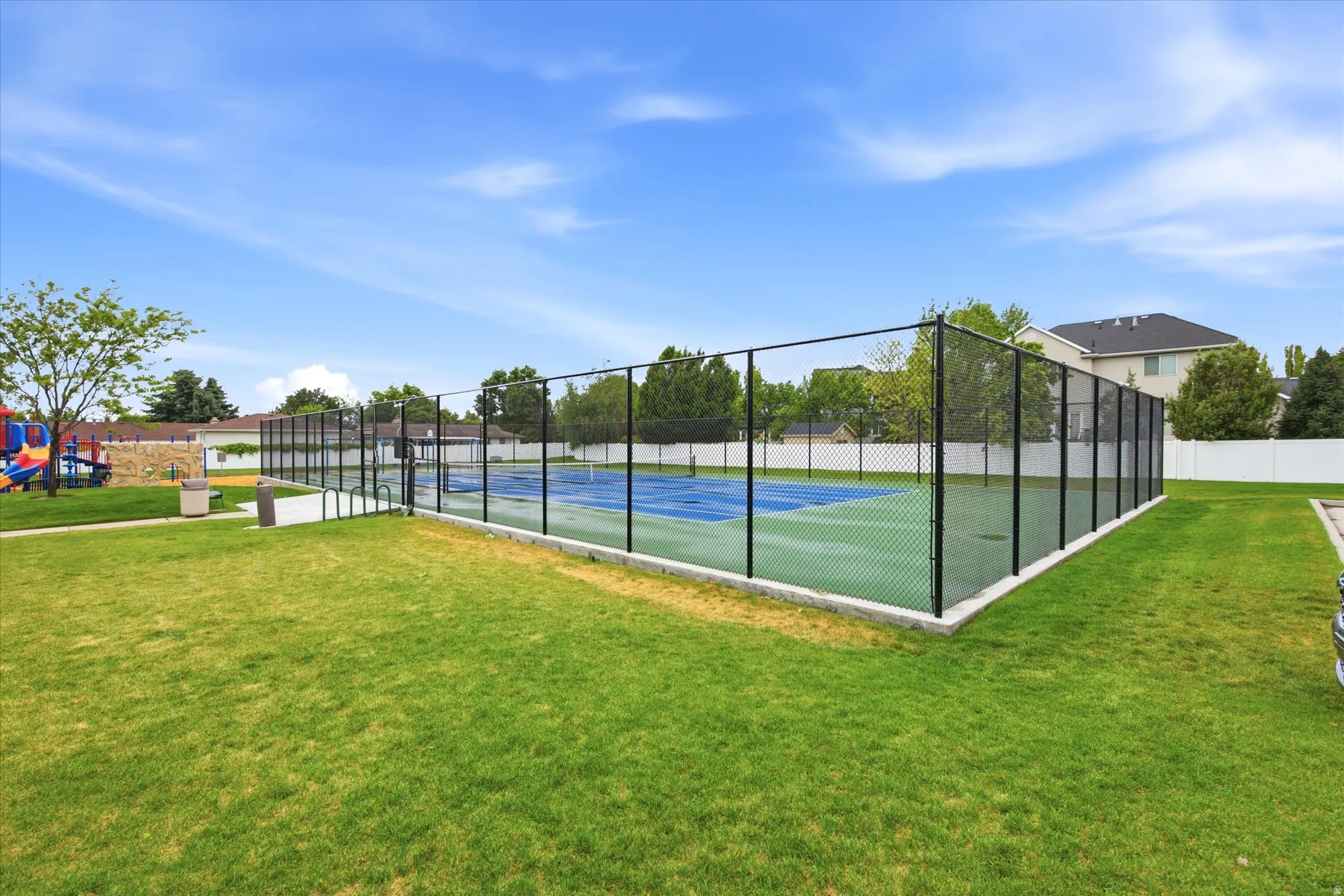 Outdoor tennis courts with chain-link fencing and a vibrant blue and green playing surface