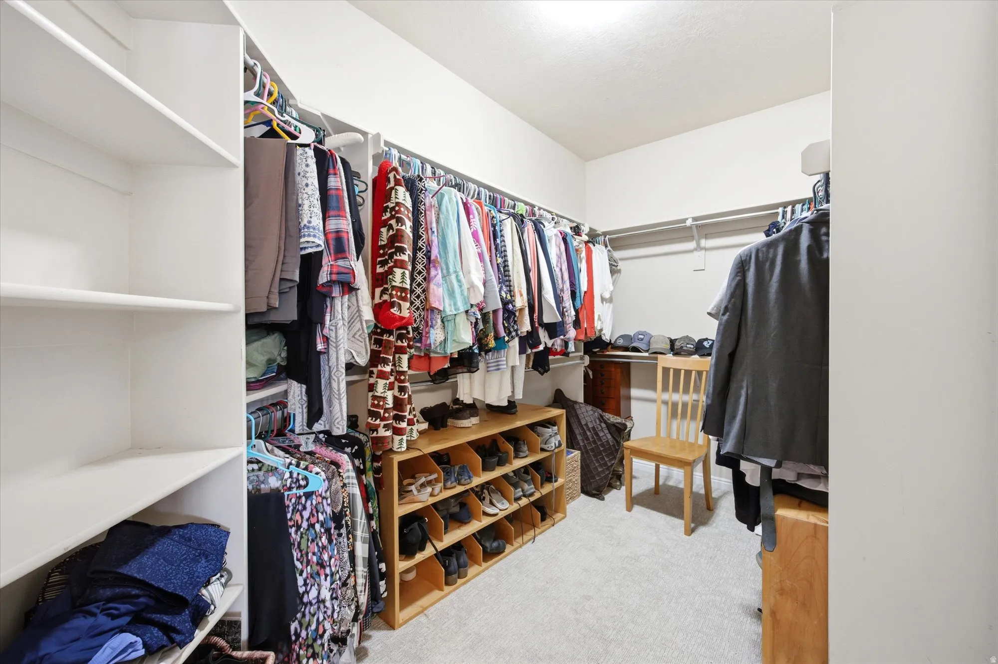 Walk-in closet with carpet flooring, white shelving units, and multiple clothing rods