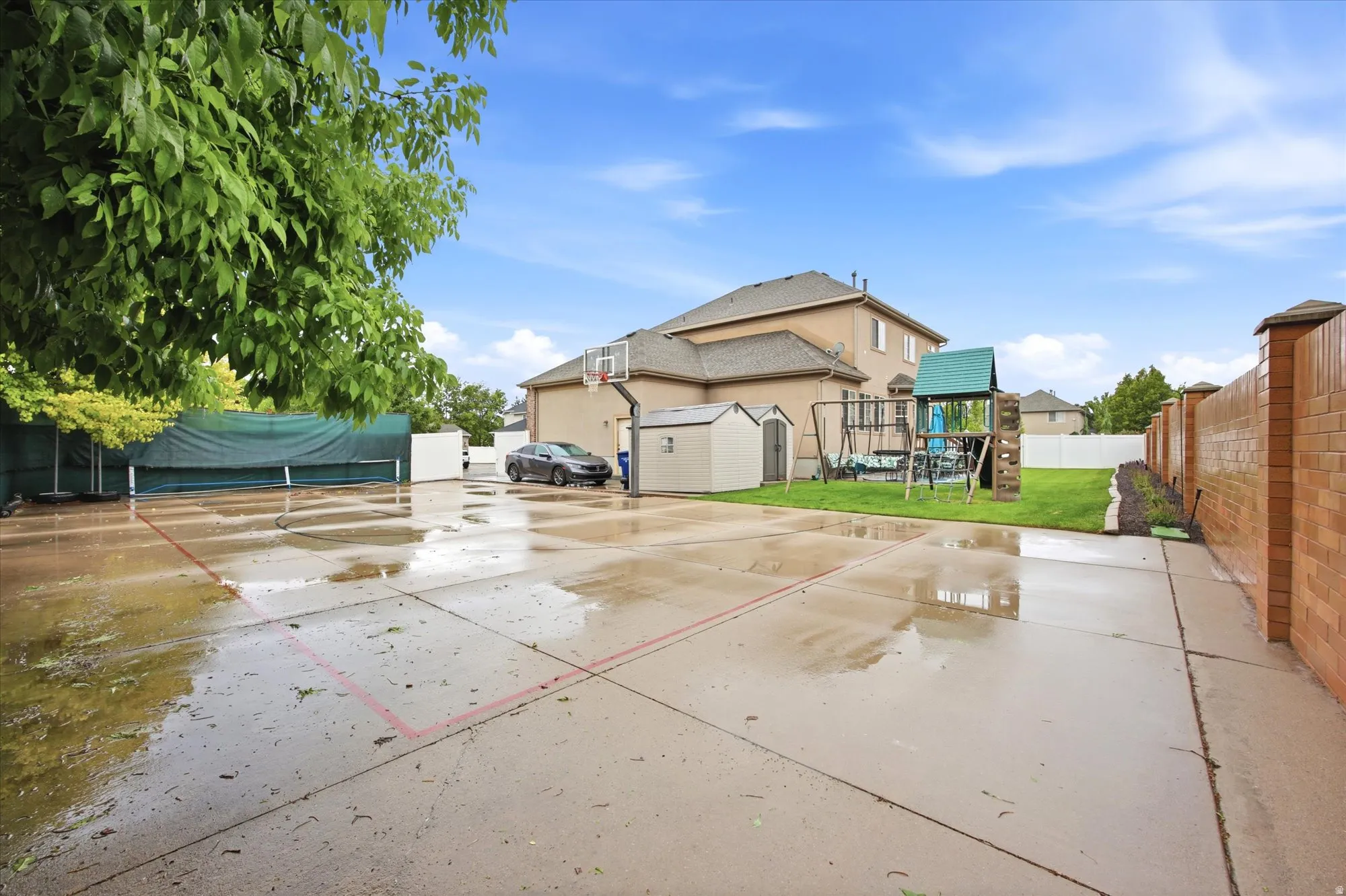 Expansive concrete patio with painted lines, featuring a basketball hoop