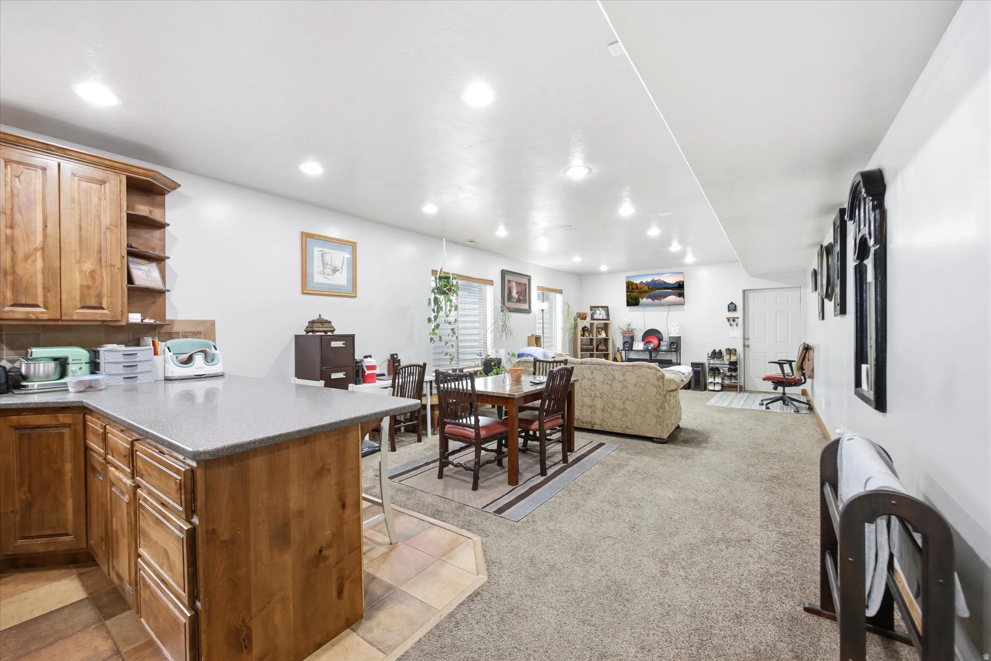 Open concept living area featuring a kitchen peninsula with wood cabinetry and a grey countertop