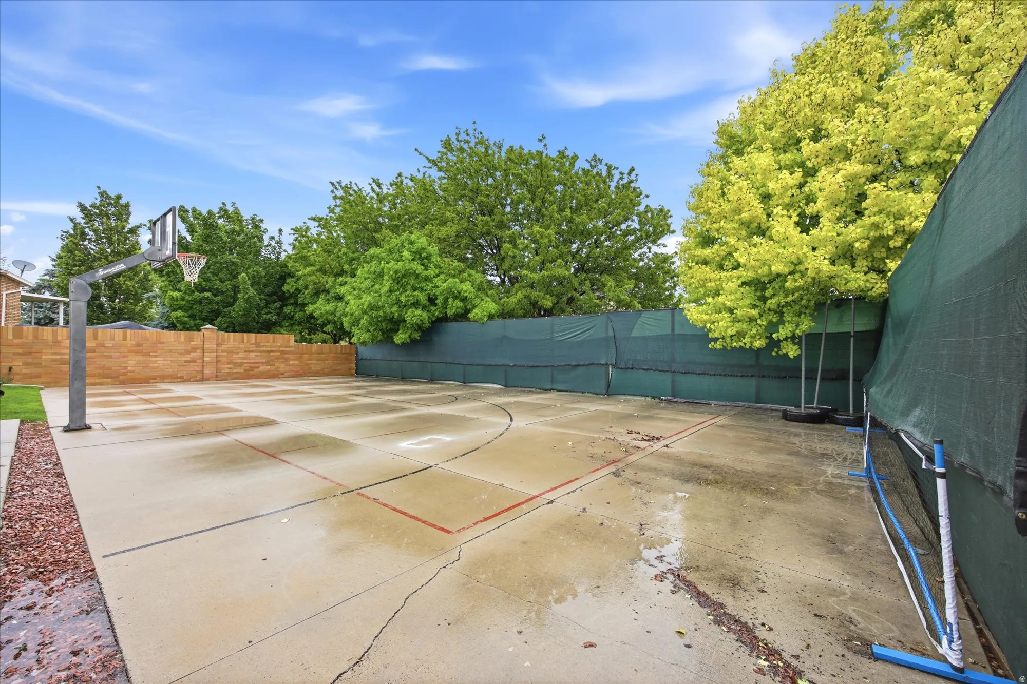 Private outdoor sports court with basketball hoop and tennis net