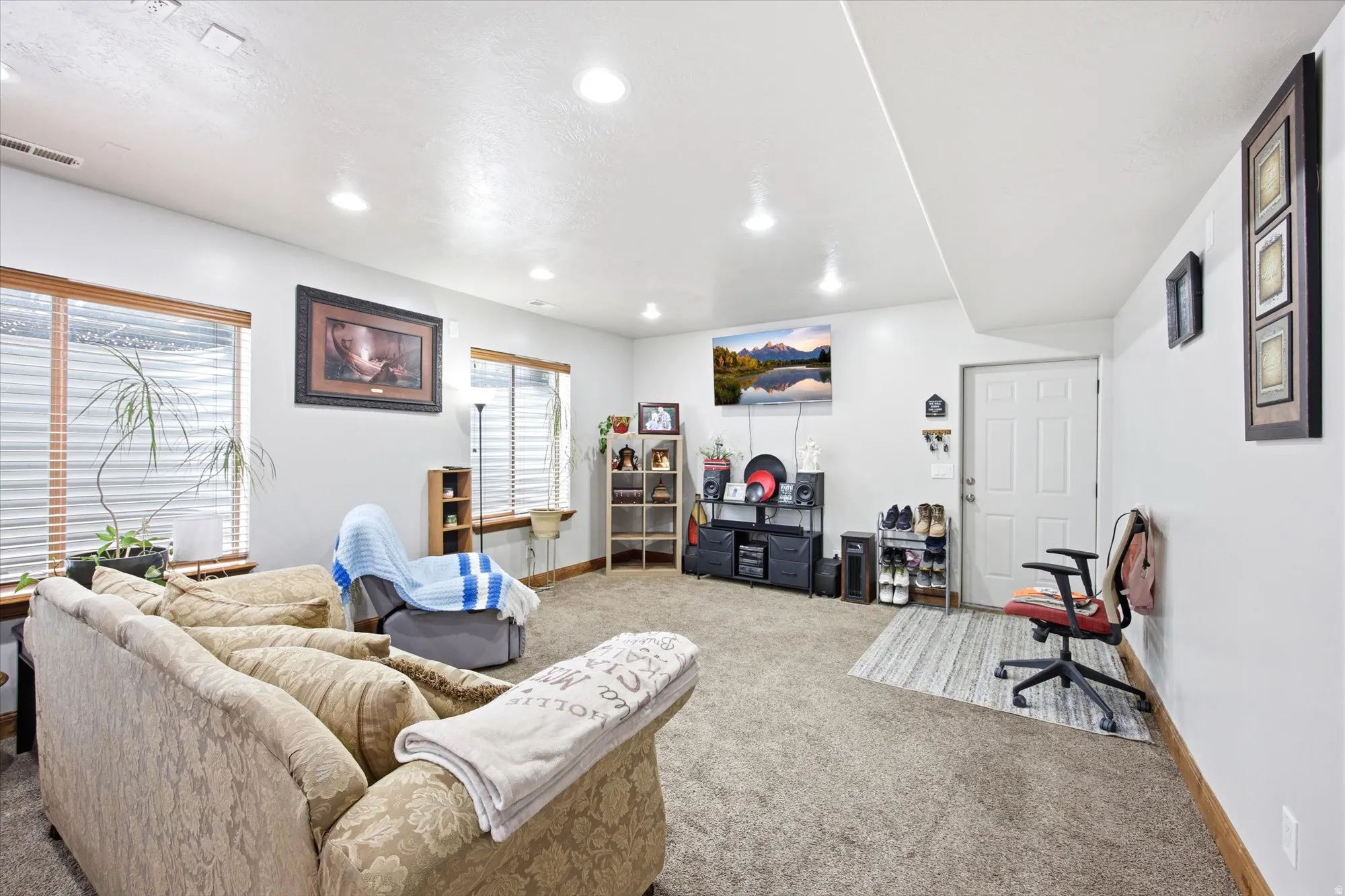 Spacious room featuring neutral carpeting, recessed lighting, white walls, and multiple windows with blinds