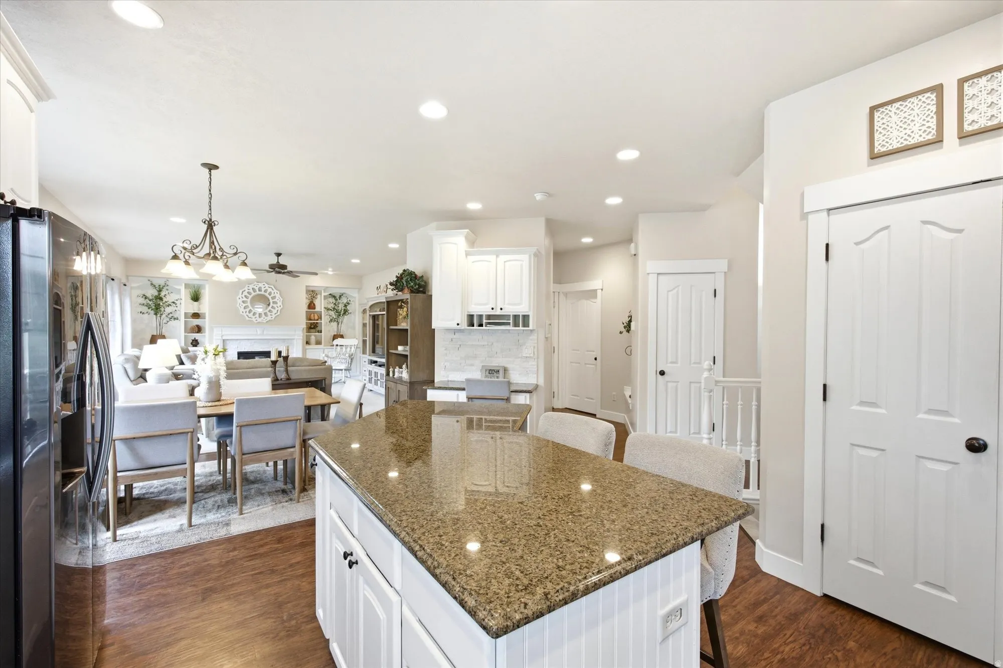 Kitchen island with a granite countertop, white paneled cabinetry, and wood-finish flooring