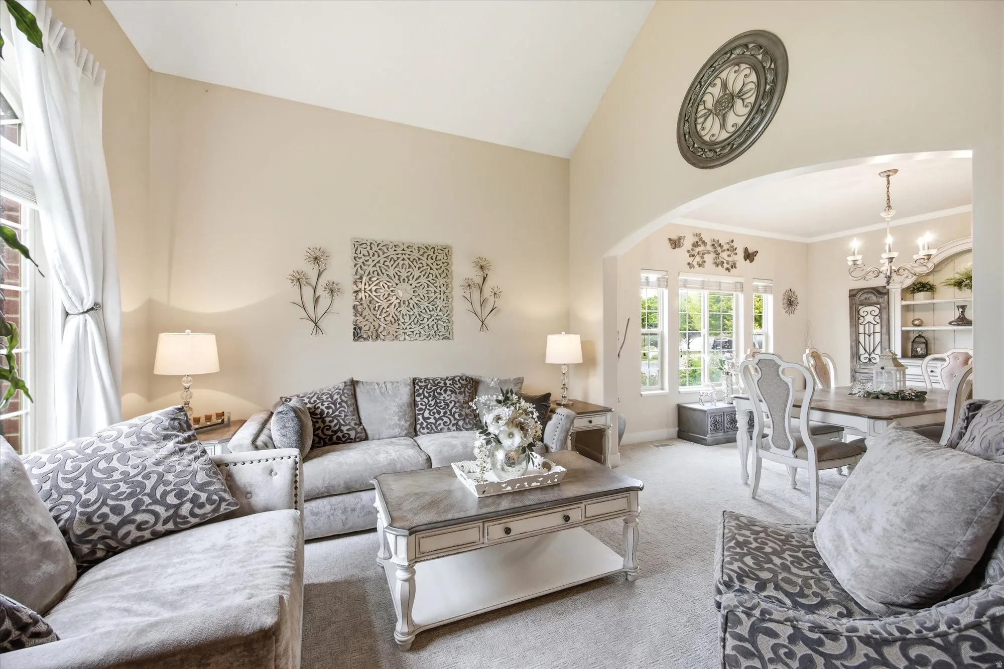 Vaulted ceiling living area with a large arched window and light-toned carpeting