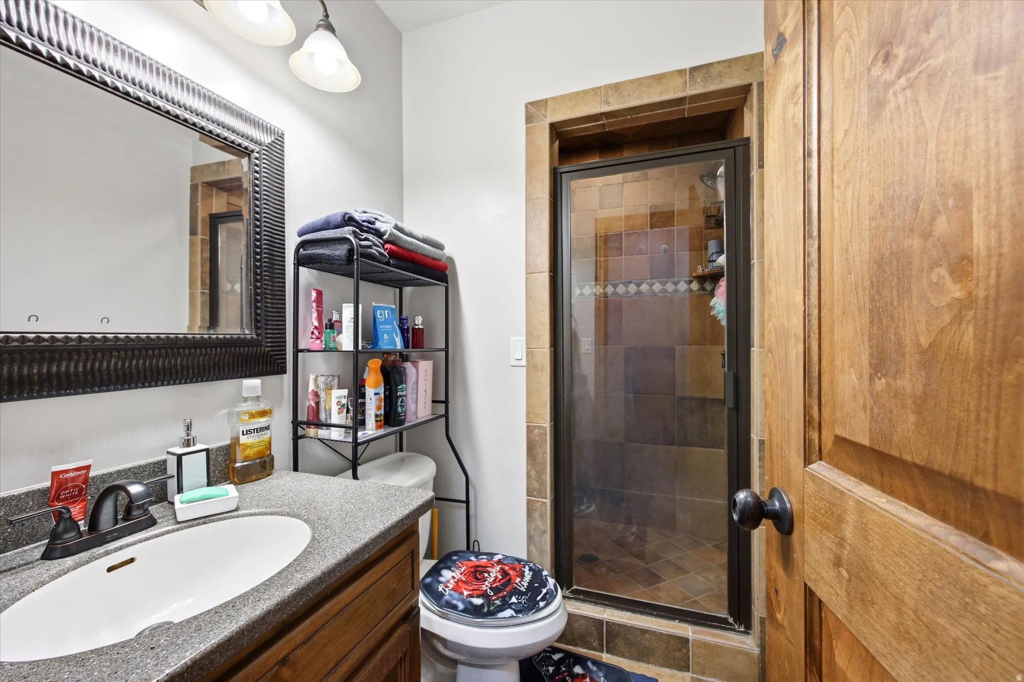 Bathroom featuring a single vanity with a stone-finish countertop, dark wood-finish cabinetry, and an oval undermount sink
