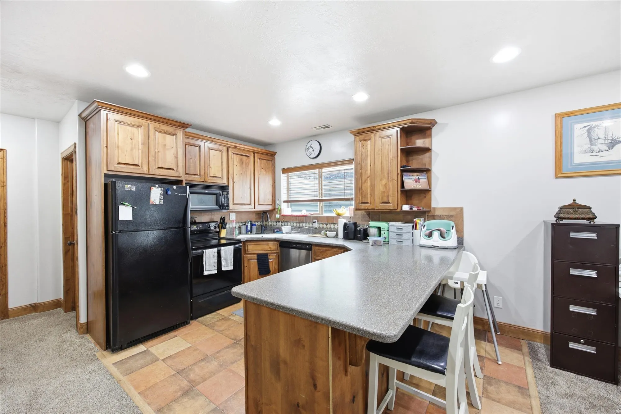 Kitchen featuring wood cabinetry, stainless steel sink, black appliances, recessed lighting, and tile flooring