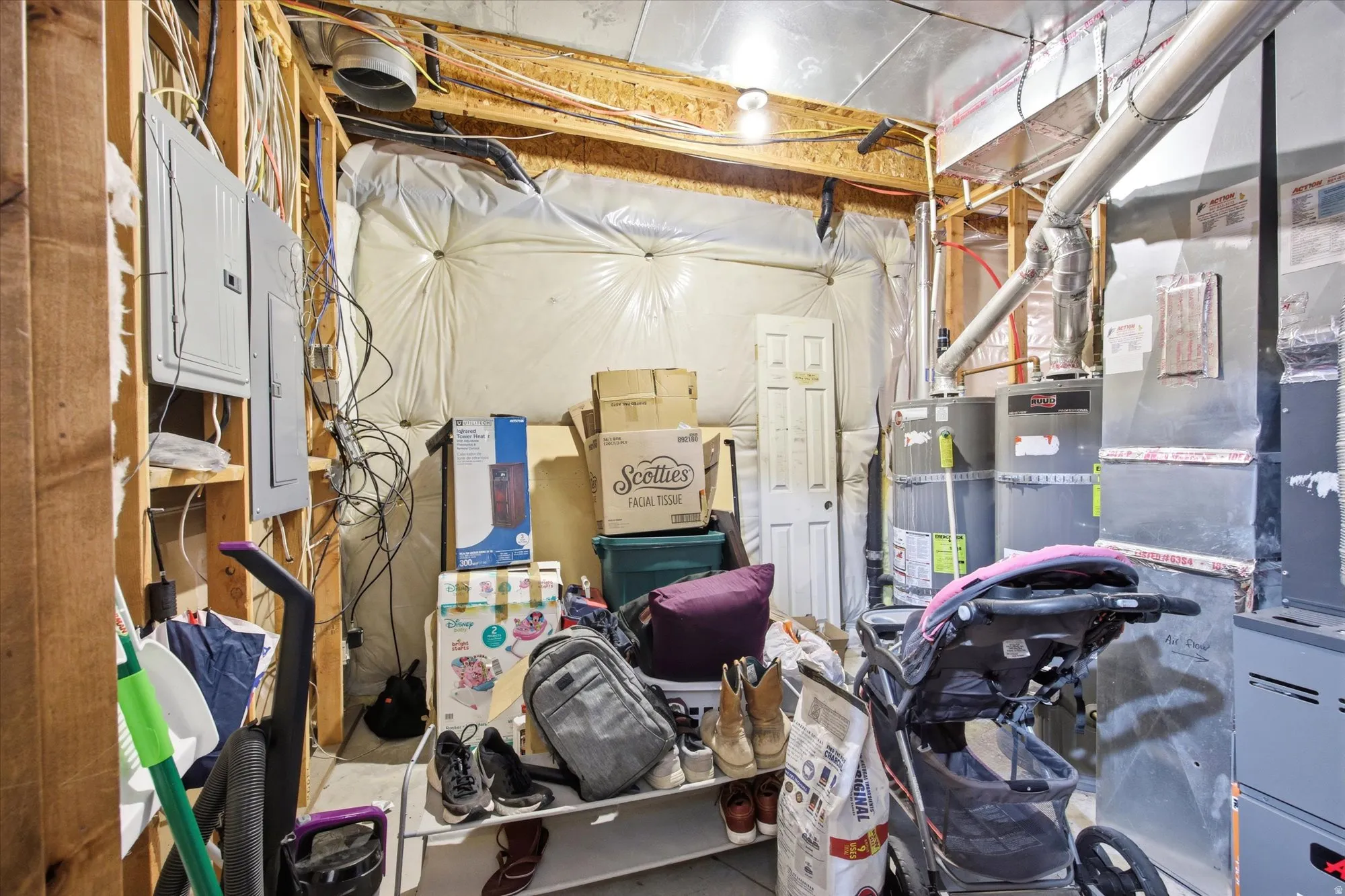 Unfinished utility space featuring exposed wooden framing, two electrical panels, and visible ductwork
