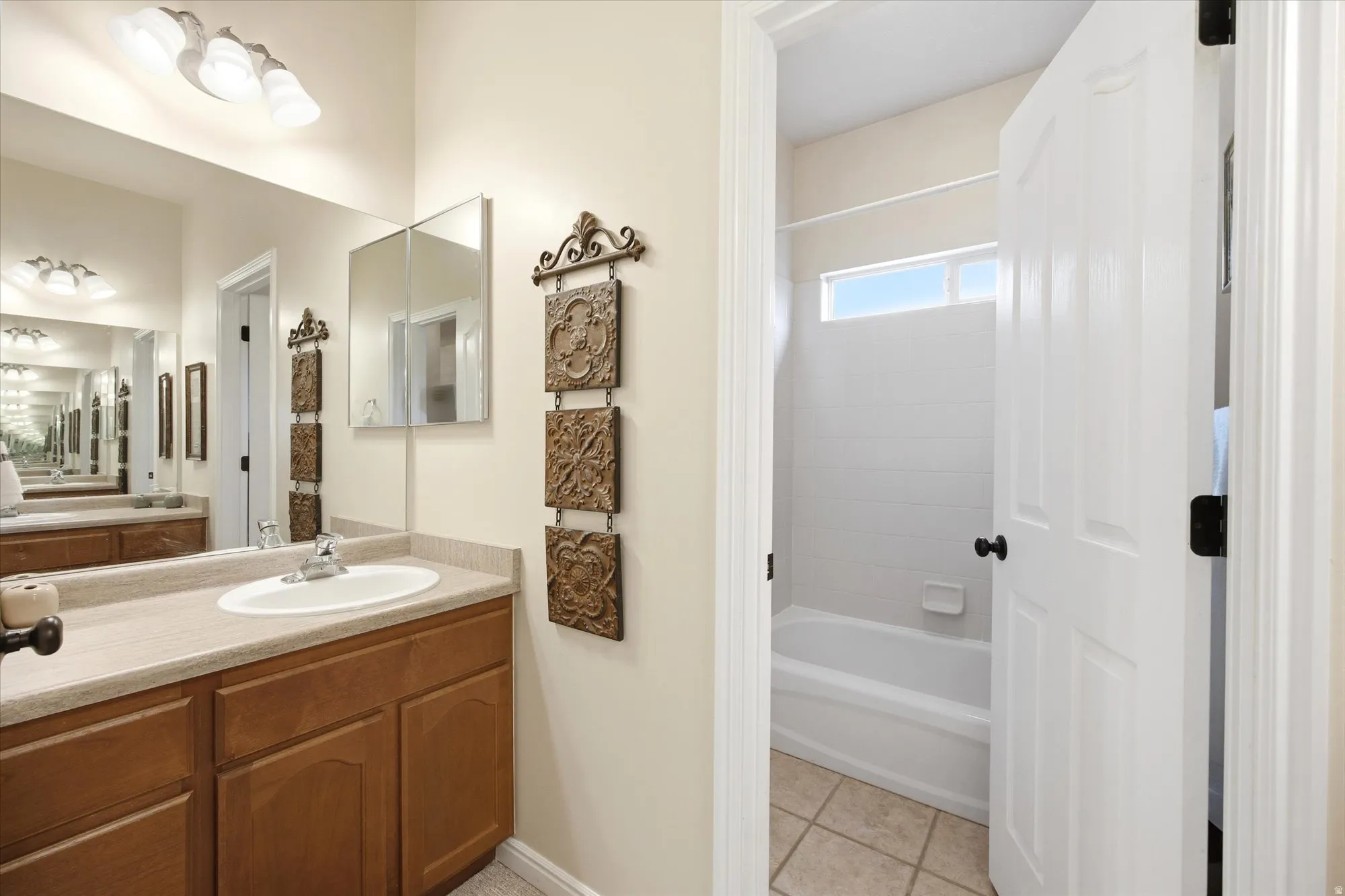 Bathroom vanity with wood cabinetry, an integrated sink, and a large wall mirror