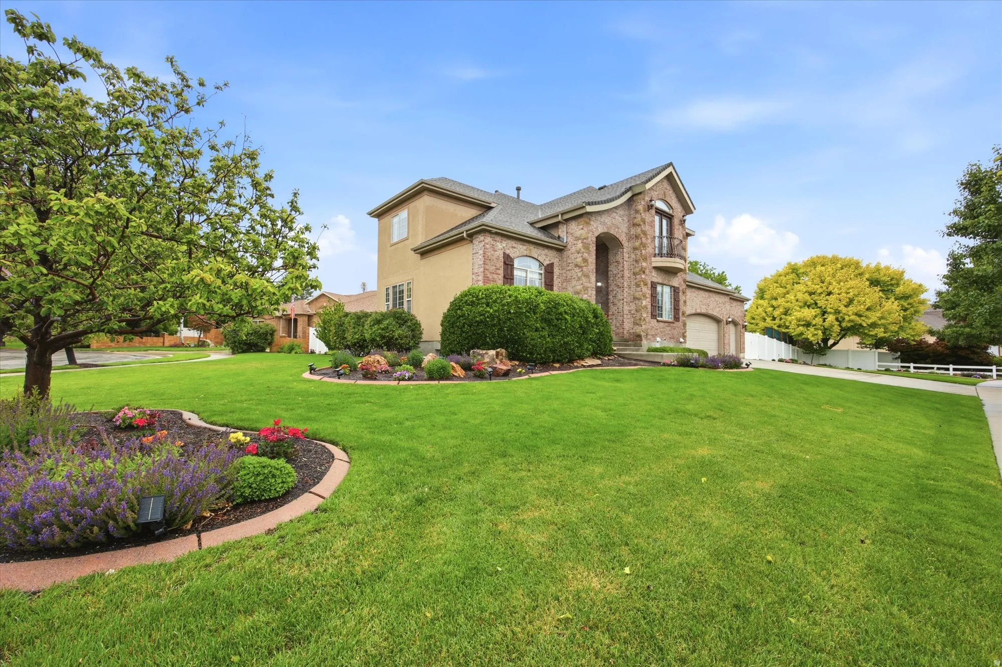 Stately residence featuring a stone and stucco exterior, arched entry, two-car garage, and a second-story balcony