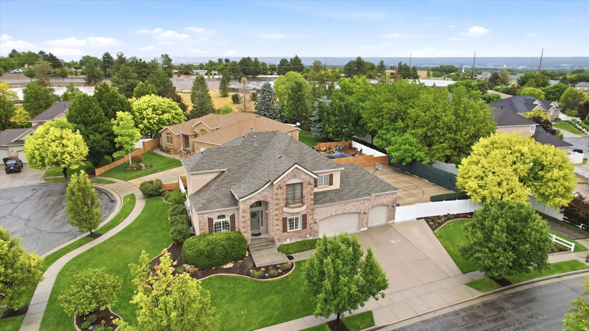Traditional style residence featuring a brick facade with stone accents, a multi-car garage, and a lush, landscaped front yard