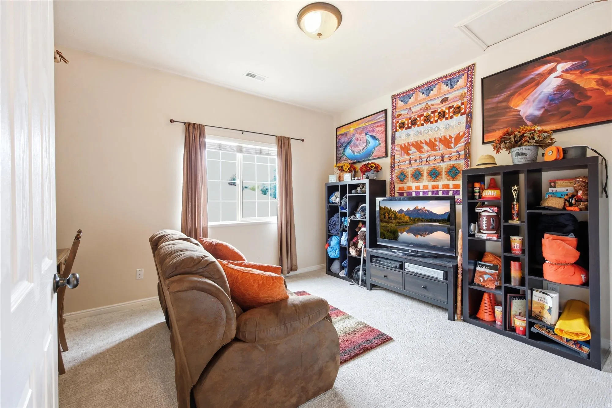 Carpeted room featuring a window with vertical grids, a flush-mount ceiling light, and a built-in access panel
