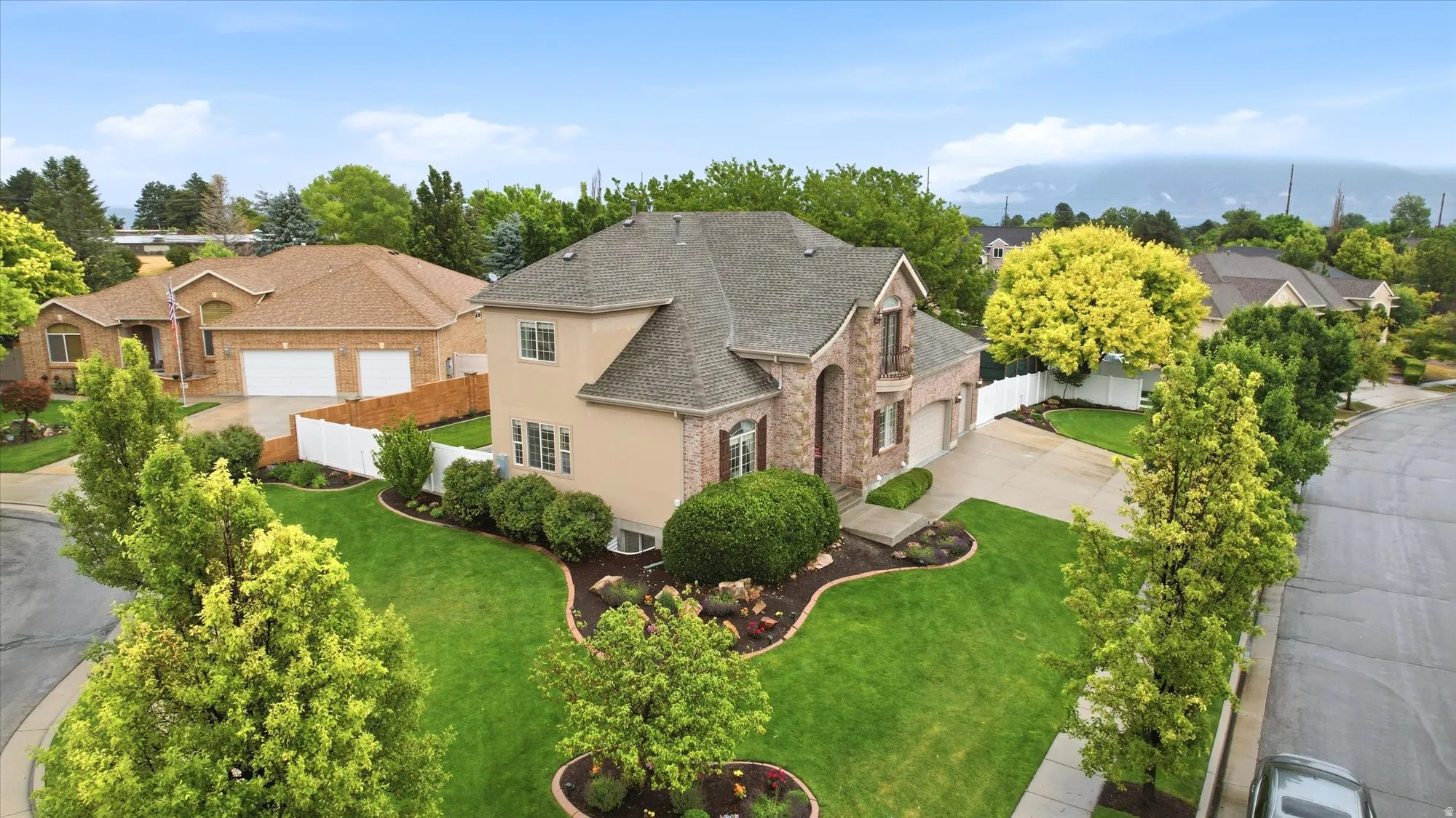 Stately residence featuring a brick and stucco exterior, a prominent gable roof, and an attached two-car garage