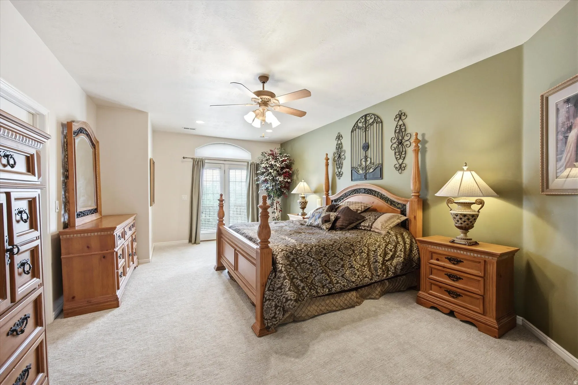 Expansive room featuring light-colored carpeting, a ceiling fan with integrated lighting, and a double French door with an arched transom