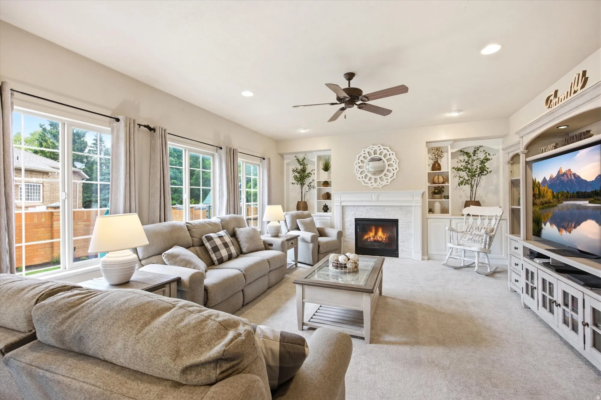 Spacious living area featuring a fireplace with a white mantel and tile surround, flanked by built-in shelving