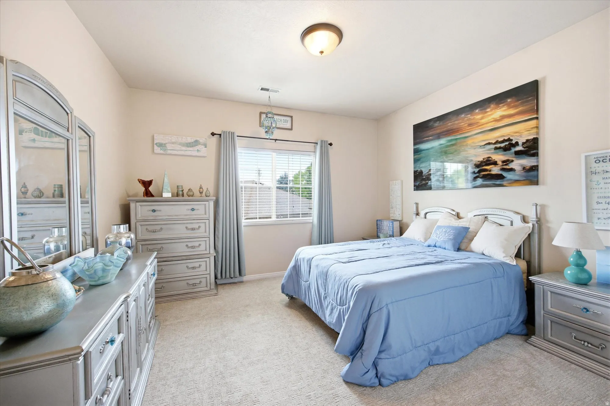 Light-colored walls complement neutral carpeting in this room featuring a window with horizontal blinds and drapery